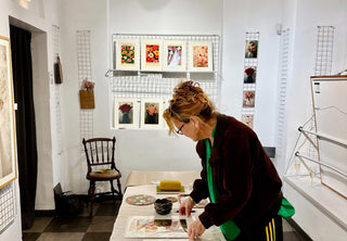 Annika Persson arranging her flower prints on a table in a white gallery room