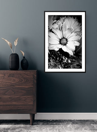 Marguerit blomst poster featuring a close-up black and white daisy flower, framed and hung on a dark wall.