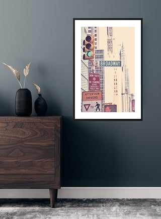 Framed Broadway street sign poster with city buildings and traffic signals, displayed above a wooden dresser.