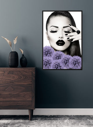 Poster of a woman with black lips and nails, posing with purple flowers, displayed on a modern wall.