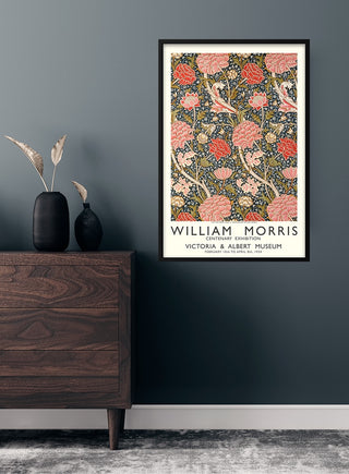 Framed William Morris cotton print poster with floral pattern, hung above a wooden dresser in a modern room.