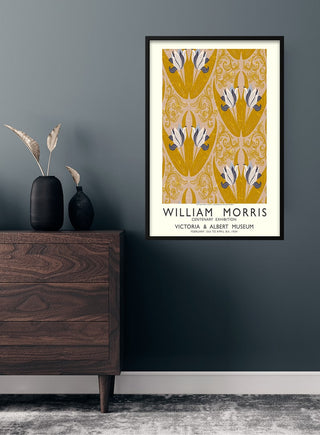 Framed William Morris tulips poster on a dark wall above a wooden dresser with decorative vases.