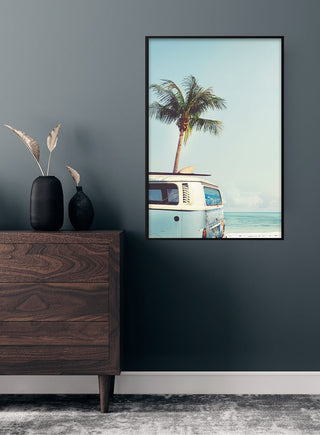 Framed poster of a vintage surfers van on a beach with palm tree and ocean, displayed above a wooden dresser.