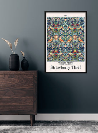 Framed Strawberry Thief - William Morris art poster hanging on a dark wall above a modern wooden dresser.