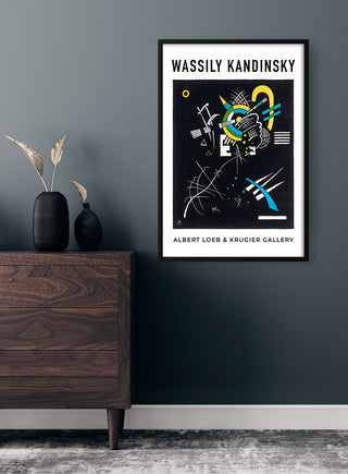 Framed Wassily Kandinsky Krugier Gallery poster on a dark wall above a wooden dresser with decorative vases.