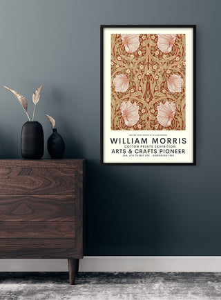 Framed William Morris cotton print poster with floral pattern, displayed on a dark wall above a wooden dresser.
