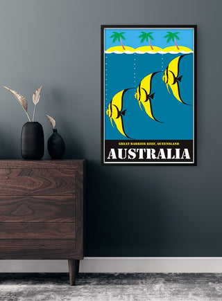 Framed Australia Vintage Plakat featuring tropical fish and palm trees, hung on a dark wall above a wooden cabinet.