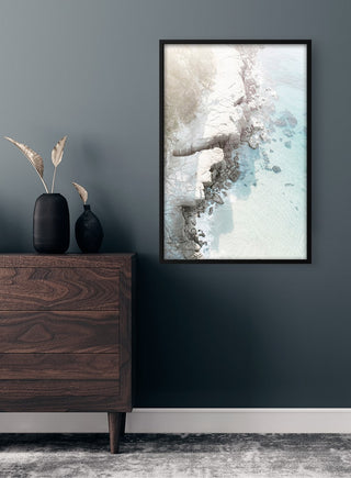 Framed Rocky beach Plakat artwork hanging on a dark wall above a wooden dresser with decorative vases.