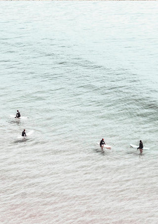 Four surfers on surfboards sit in calm, pale water seen from above for Surfers in Water Plakat.
