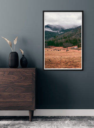 Framed Mountain in the Background Naturposter on a dark wall above a wooden dresser with decorative vases.