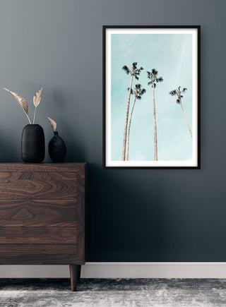 Framed Tall Palms Plakat on wall above dark wood dresser with decorative vases in modern room setting.