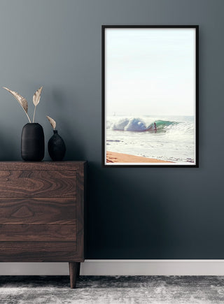 Framed Surfer in the Waves Plakat on a dark wall above a wooden dresser with minimalist decor.