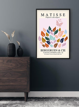 Framed Matisse-inspired papier decoupe poster with colorful leaf shapes on a modern wall above a wooden dresser.