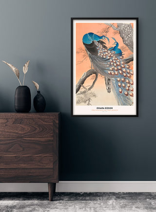 Two peacocks on a branch artwork by Ohara Koson, framed and displayed above a modern wooden dresser.