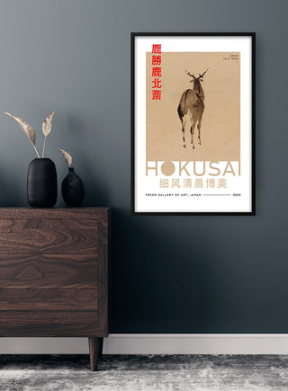 Framed Hokusai Deer Plakat on a gray wall above a wooden dresser with vases and dried plants.