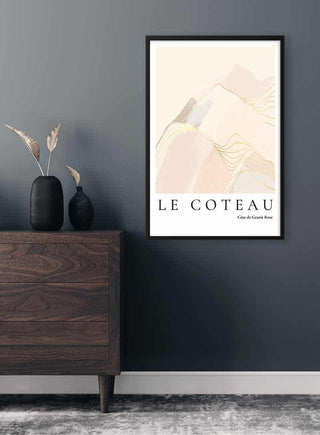Framed Cote de Granit Rose poster with abstract mountain art hanging on a dark wall above a wooden dresser.