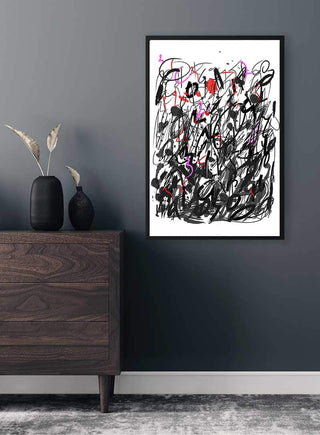 Abstract street art poster with bold black, red, and pink strokes hanging on a dark gray wall above a wooden dresser.