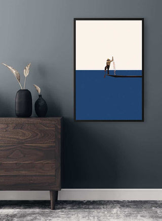 Framed "Fishing for compliments" by Maarten Léon displayed on a dark wall above a wooden dresser.