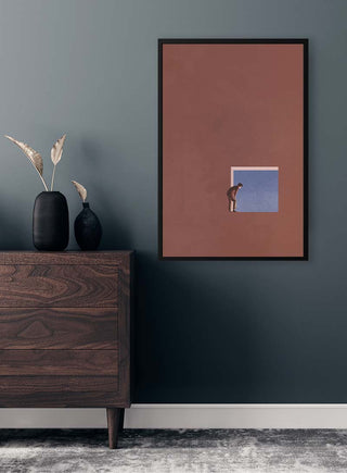 Framed "Curiosity" by Maarten Léon on a dark wall above a wooden dresser with vases and dried leaves.