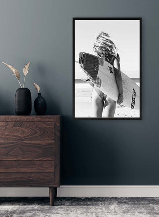Black-and-white photo of a surfer holding a board, displayed in a modern room; Surfers Fashion wall art product.