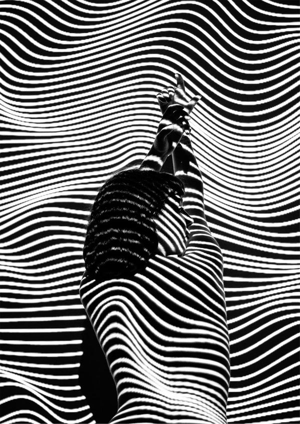 A model in black and white fashion poses with abstract striped patterns creating a bold visual effect.