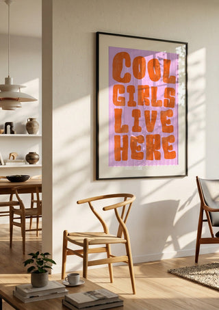 Cool girls live here by Ohkimiko in a black frame in a bright dining room with wooden chairs