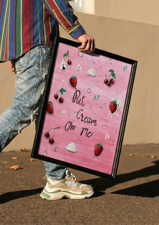 Put Cream On Me by KG Studio carried in a black frame along a sunny street