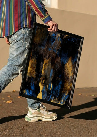 Gold on Blue by Kristof ellertz carried in a black frame along a sunny street