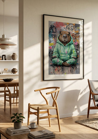 Capybara x Grafitti by Decker Studios in a black frame in a bright dining room with wooden chairs