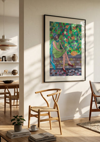 The Garden Wall by Camilla Nilsson in a black frame in a bright dining room with wooden chairs