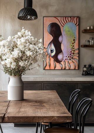Two Heads, One Eye by Shimmering Ugly in a black frame above a rustic table with white flowers