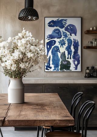 Creatures 2 by Lena Galé in a black frame above a rustic table with white flowers