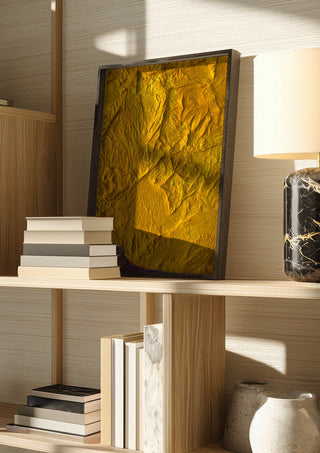 Das Licht in uns by Sophie Schillen in a dark frame on a wooden shelf beside books and a lamp