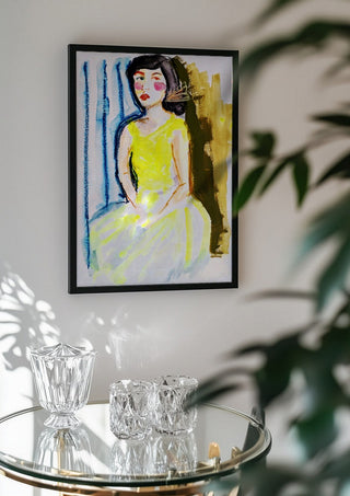 Yellow Dress by DNF in a black frame above a glass table with crystal glassware