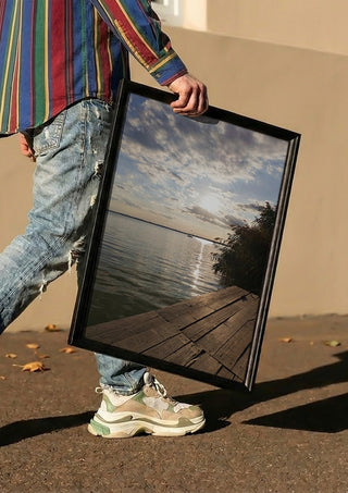 Sunset at the Lakeside Dock by Bora Kőhalmi carried in a black frame along a sunny street