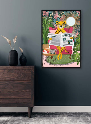 Framed artwork of a leopard reading newspapers on a pink chair, surrounded by plants, displayed above a dresser.
