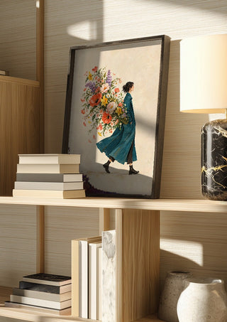 A Garden in Her Pocket by Matthews Gallerie in a dark frame on a wooden shelf beside books and a lamp