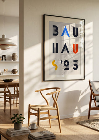 Bauhaus Letters by Neil Stevens in a black frame in a bright dining room with wooden chairs