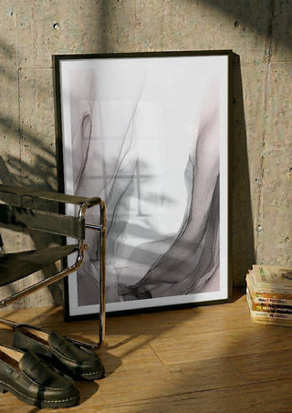 Traces of Wind by Anna Dormir in a black frame leaning against a concrete wall by a steel chair