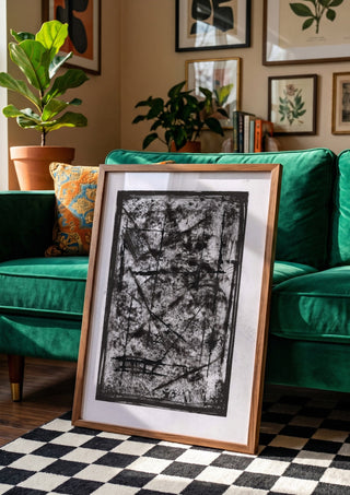Black Field by David Pernecker in a wooden frame leaning against a green velvet sofa on a chequered floor