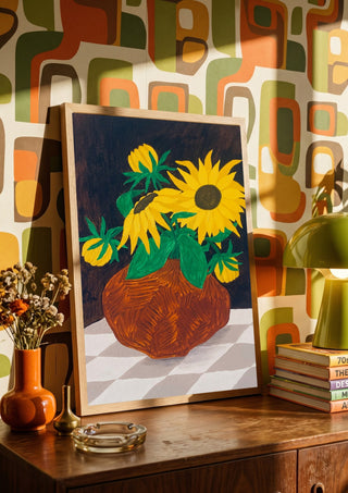 Gula blomster på rutig duk by Rebecka Hansson in a wooden frame on a sideboard against a retro patterned wall