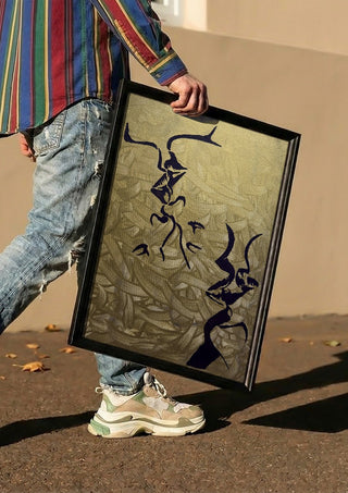 Whispers in Gold by Bibi carried in a black frame along a sunny street