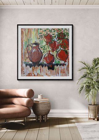 Pomegranates by Dina in a black frame above a pink armchair beside a palm