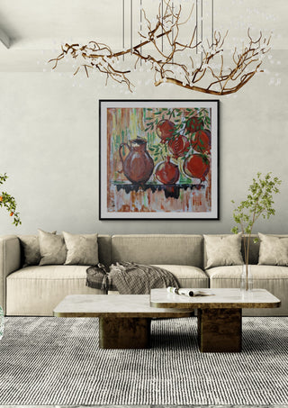 Pomegranates by Dina in a black frame above a beige sofa under a branch chandelier