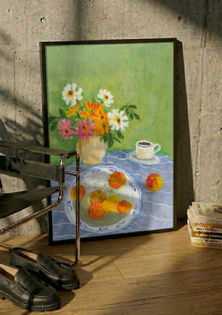 February Zinnias by Deblina Dey in a black frame leaning against a concrete wall by a steel chair