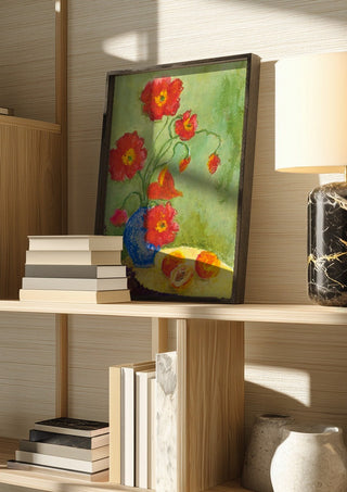Poppies by Deblina Dey in a dark frame on a wooden shelf beside books and a lamp