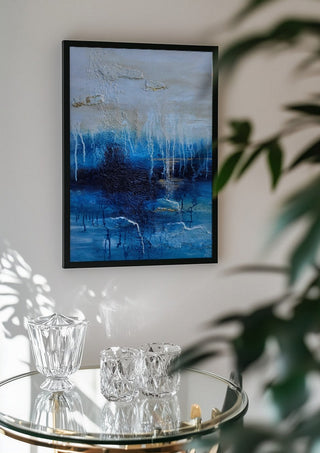Rising Light by Sabine Halbrock in a black frame above a glass table with crystal glassware