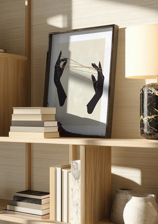 Unclear plans by Nari in a dark frame on a wooden shelf beside books and a lamp
