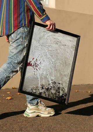 Pain by Tonia carried in a black frame along a sunny street