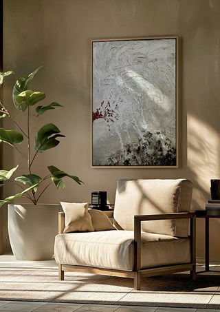 Pain by Tonia framed above a beige armchair beside a potted plant